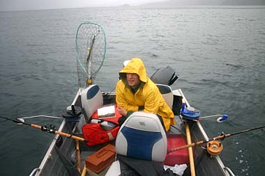 Man in yellow jacket huddles in boat